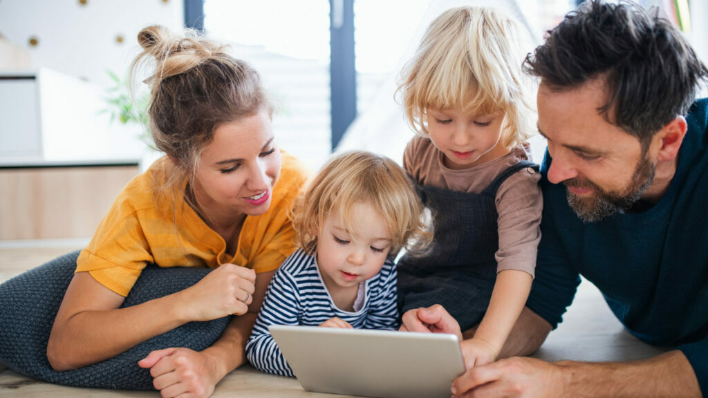 Parents at home with young children playing on a tablet together